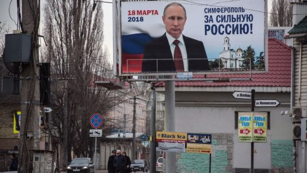 Peole walk past campaign billboards of Russian President Vladimir Putin, reading "Simferopol for the Strong Russia! Vladir Putin" in Simferopol on Mar. 9, 2018. Russians will vote Mar. 18 during presidential election that Vladimir Putin is almost guaranteed to win.
(STRINGER / AFP)