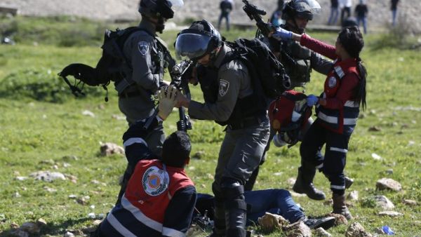 Palestinian Civil Defense volunteers scuffle on Mar. 12, 2018 in the West Bank town of Birzeit, near Ramallah, with Israeli soldiers as they attempt to give aid to an injured Palestinian demonstrator during a protest by students of the Birzeit University against the arrest of the the head of Palestinian student council by an Israeli undercover commando. (ABBAS MOMANI / AFP)