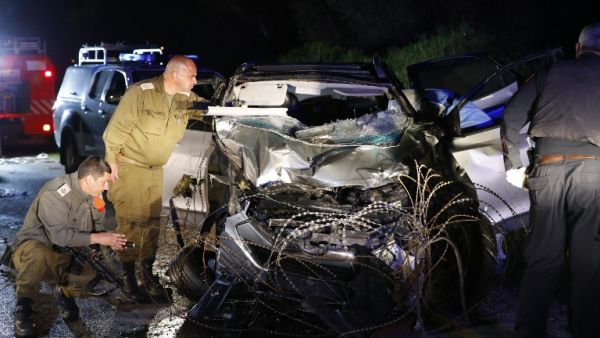 Israeli security forces and forensics inspect the destroyed vehicle that was used by a Palestinian assailant in a car ramming attack targeting a group of Israeli soldiers near Mevo Dotan in the north of the occupied West Bank on Mar.16, 2018. 
(Jack GUEZ / AFP)