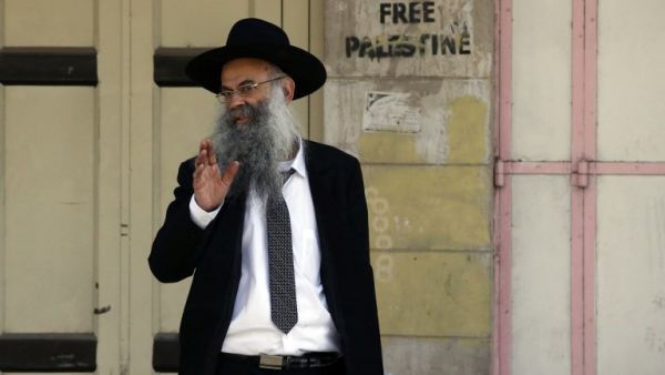 An Israeli settler walks passed Palestinian shops, closed by Israeli soldiers during the settlers' visit, in the occupied West Bank city of Hebron on Mar. 2, 2018, as he makes his way to visit the tomb of Othniel Ben Kenaz. 
(HAZEM BADER / AFP)