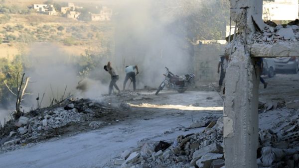 Syrians use dirt to put out a fire at the scene of a reported air strike in the district of Jisr al-Shughur, in the Idlib province, on September 4, 2018. (Zein Al RIFAI / AFP)