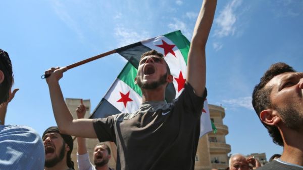 Syrian protesters wave the flag of the opposition as they demonstrate against the regime and its ally Russia, in the rebel-held city of Idlib on September 7, 2018 (ZEIN AL RIFAI/AFP)