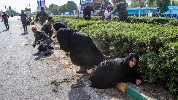 This picture taken on September 22, 2018 in the southwestern Iranian city of Ahvaz shows Iranian women and soldiers taking cover next to bushes at the scene of an attack on a military parade (AFP)