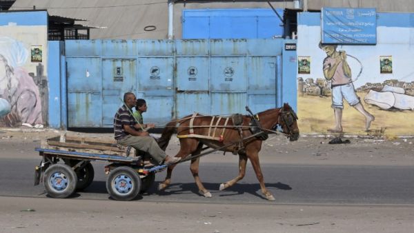 Men on a horse-drawn cart pass in front of an aid distribution center run by the United Nations Relief and Works Agency (UNRWA) in Gaza City (AFP)