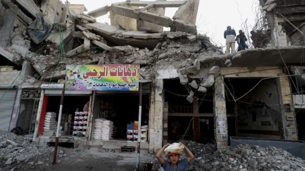 Labourers clear debris from a destroyed building in the Syrian city of Raqa (AFP)