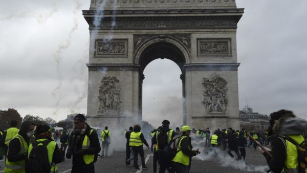 Protestors of the yellow vest (gilet jaune) movement walk past the Arc of Triomphe on the Champs Elysees in Paris, on November 24, 2018 during a protest against rising oil prices and living costs. (AFP)