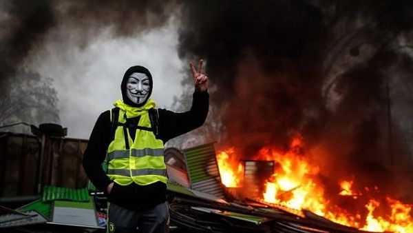 A protester wearing a Guy Fawkes mask makes the 'Victory' sign during a protest of the Yellow Vests against rising oil prices and living costs, on December 1, 2018, in Paris. (AFP)