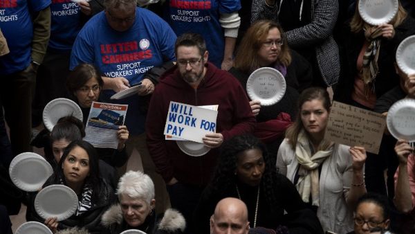 A federal worker stands with a placard reading "Will Work For Pay" as other federal employees stage a rally to call for a vote on the shutdown. (AFP/ File)