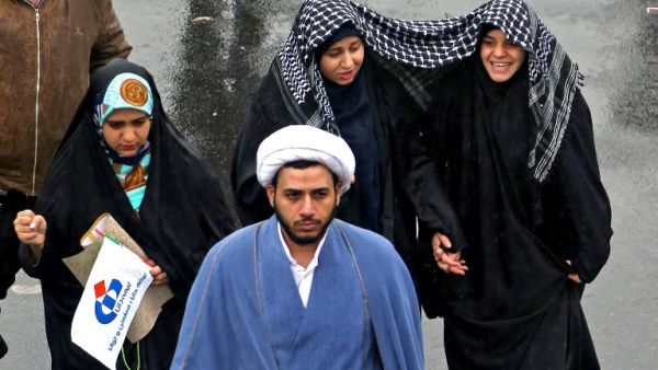 Iranian women march together in the rain under a shared scarf during a ceremony celebrating the 40th anniversary of Islamic Revolution in the capital Tehran on February 11, 2019. 
ATTA KENARE / AFP 