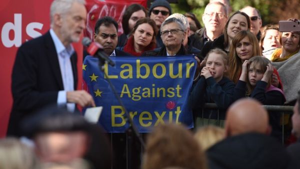 Labour party supporters hold up an anti-Brexit placard as they listen to opposition Labour Party leader Jeremy Corbyn (L) at a rally on February 23, 2019. (AFP/File)