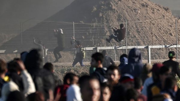 Palestinian protesters climb the border fence with Israel during clashes following a demonstration near the fence along the border with Israel, east of Gaza City, on March 8, 2019. (MAHMUD HAMS / AFP)