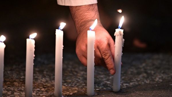 A well-wisher places one of 49 candles as he pays respects to victims outside the hospital in Christchurch (AFP)