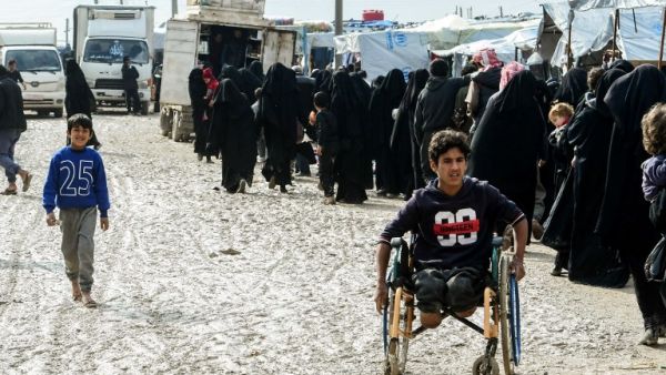 Veiled women, living in al-Hol camp which houses relatives of Islamic State (IS) group members, stand in queue to receive goods in the camp in al-Hasakeh governorate in northeastern Syria on March 28, 2019. 
GIUSEPPE CACACE / AFP 