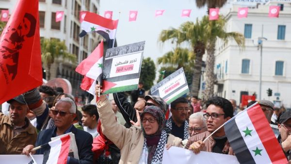 Tunisians hold the Syrian and Palestinian flags as they demonstrate against the Arab League Summit and the United States’ recognition of Israeli sovereignty over the Golan Heights. (AFP)