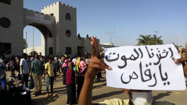 A Sudanese protester holds a placard during a demonstration in front of the military headquarters in the capital Khartoum on April 9, 2019. The writing on the placard reads in Arabic : "We have chosen death, hey dancer", referring to the president. (AFP)