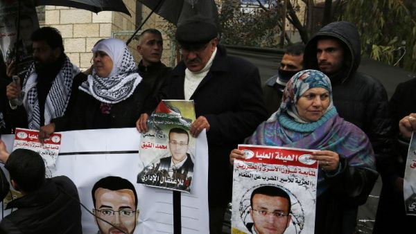 Supporters of hunger striking Palestinian prisoner Mohammed al-Qiq hold portraits as they demonstrate in solidarity with him on February 7, 2016, outside the offices of the International Committee of the Red Cross (ICRC) in the West Bank city of Ramallah. (AFP/Abbas Momani, File)