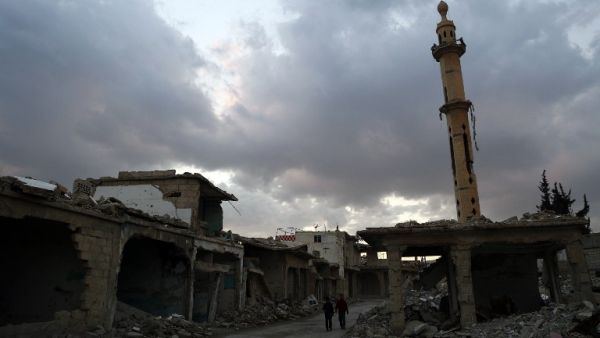 Syrian children walk past heavily damaged buildings in the rebel-held town of Douma, on the eastern edges of the capital Damascus on February 27, 2016, on the first day of the landmark ceasefire agreement. (AFP/Sameer al-Doumy)