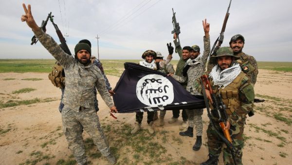 Iraqi Shia fighters from the Popular Mobilization units pose with a Daesh group flag on March 3, 2016, during an operation in the desert of Samarra aimed at retaking areas from militants. (AFP/Ahmad al-Rubaye)