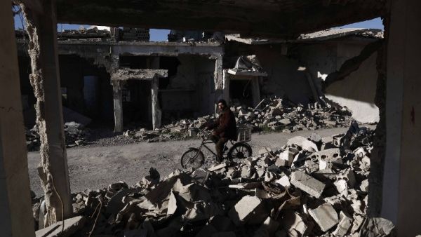 A Syrian man rides his bicycle past the rubble of destroyed buildings on March 7, 2016, in the rebel-held town of Douma, on the outskirts of the capital Damascus. (AFP/Sameer Al-Doumy)