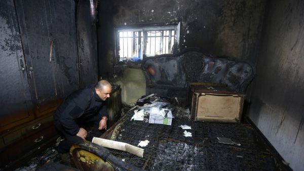 A Palestinian police member inspects the damage inside a burnt-out house belonging to a key witness to an arson attack which took place last year by Jewish extremists that killed a Palestinian family, in the Israeli occupied West Bank village of Duma, after fire broke out in the home in the early hours of March 20, 2016. (AFP/Jaafar Ashtiyeh)