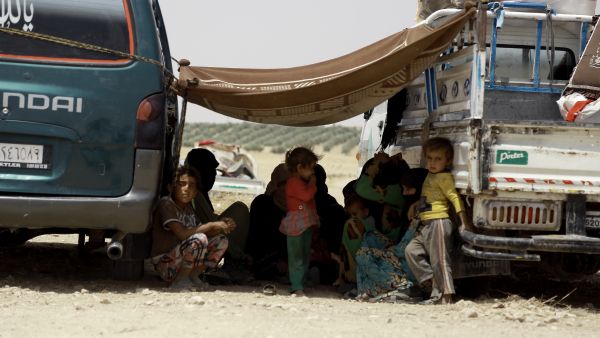 Syrian families, who fled the fighting between Syrian Arab Coalition fighters and Daesh in the town of Manbij, rest under a blanket at an encampment on the outskirts of the town, 20km away from the center, on June 4, 2016. (AFP/Delil Souleiman)
