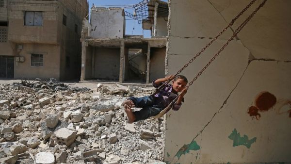 A Syrian boy plays on a swing in a destroyed building in the rebel-held town of Douma, on the eastern outskirts of Damascus, as Muslims celebrate the third day of the Eid al-Adha holiday on September 3, 2017. (AFP)