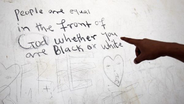 A sub-Saharan migrant shows writings on a wall as he waits at the Qanfouda detention center, in the southern outskirts of Benghazi, before being repatriated on Dec. 2, 2017. 
(Abdullah DOMA / AFP)
