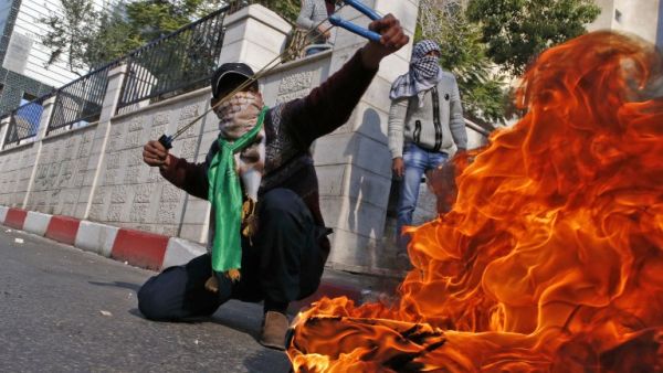 A Palestinian protestor uses a sling shot to throw stones towards Israeli security forces during clashes after the Friday prayers in the city centre of the West Bank town of Hebron. (HAZEM BADER / AFP)