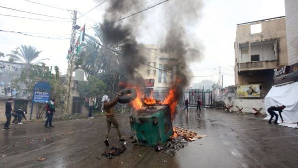 A protester throws a tire on a fire during a demonstration outside the US embassy in Awkar, on the outskirts of the Lebanese capital Beirut, on Dec. 10, 2017, to protest against Washington's decision to recognize Jerusalem as the capital of Israel (ANWAR AMRO/AFP)