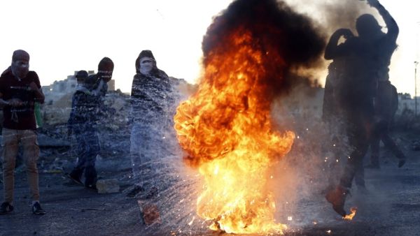 A Palestinian demonstrator kicks a burning tire during clashes with Israeli forces near an Israeli checkpoint in the West Bank city of Ramallah following the U.S. president's controversial recognition of Jerusalem as Israel's capital. (ABBAS MOMANI / AFP)