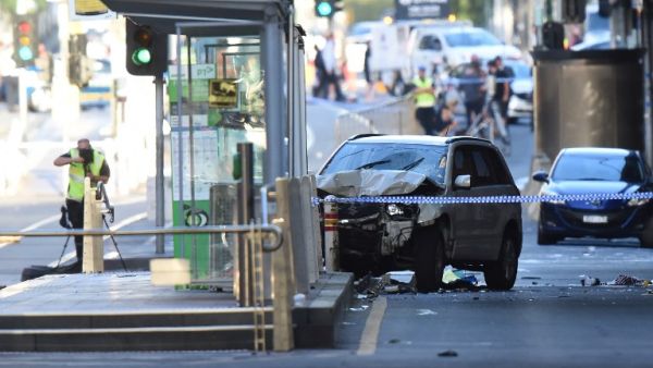A white SUV (C) sits in the middle of the road as police and emergency personnel work at the scene of where a car ran over pedestrians in Flinders Street in Melbourne on Dec. 21, 2017 (Mal Fairclough / AFP)