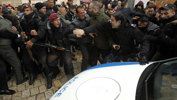 Palestinian policemen push away protesters from the convoy of Jerusalem's Greek Orthodox Patriarch Theophilos III outside the church of Nativity in the West Bank town of Bethlehem on Jan. 6, 2018 ahead of a Christmas service according to the Eastern Orthodox calendar (MUSA AL SHAER/AFP)