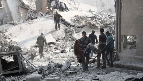 A volunteer from the Syrian Civil Defence (known as the White Helmets) carries a wounded girl after digging her out of the rubble following an air strike on Hamouria on January 9, 2018 (ABDULMONAM EASSA / AFP)