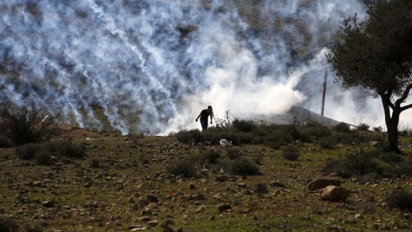 Palestinians run for covers from smoke-grenades during clashes with Israeli security forces following a demonstration in support of Palestinian prisoners on Jan. 13, 2018, in the West Bank village of Nabi Saleh (ABBAS MOMANI / AFP)