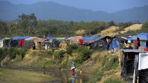 This photo taken on Jan. 23, 2018 shows Rohingya Muslim refugees crossing a canal next to a settlement near the 'no man's land' area between Myanmar and Bangladesh in Tombru in Bangladesh's Bandarban district (Munir UZ ZAMAN / AFP)