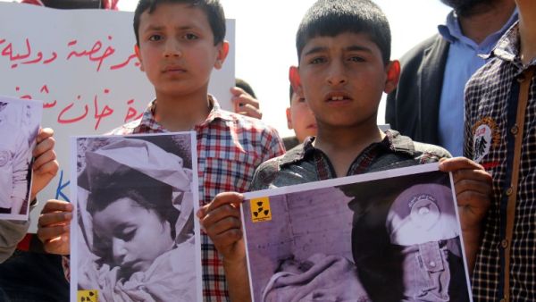 In this file photo taken on April 7, 2017, Syrian residents of Khan Sheikhun hold placards and pictures during a protest condemning a suspected chemical weapons attack on the town that killed at least 86 people (Omar haj kadour / AFP)
