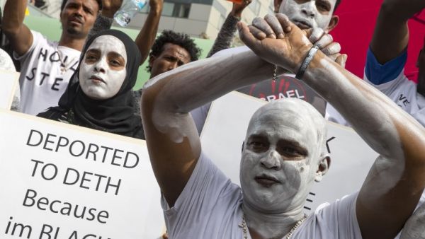 African migrants demonstrate with white paint on their faces and with their hands crossed, outside the Embassy of Rwanda in the Israeli city of Herzliya on Feb. 7, 2018 (JACK GUEZ / AFP)