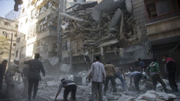Syrian civilians and rescuers gather at the site of an air strike. (AFP)
