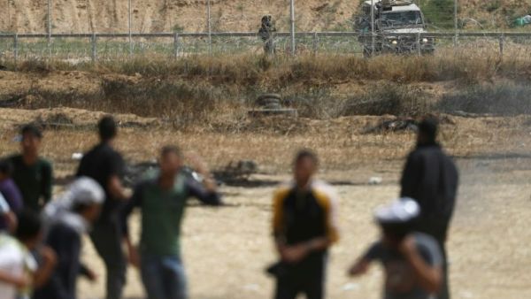 An Israeli soldier aims his weapon as Palestinian protesters gather near the border fence with Israel (AFP/File Photo)	