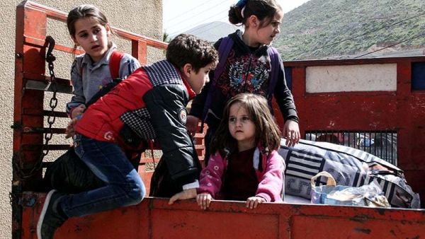 Syrian child refugees ride in the back of a pickup truck prior to their evacuation from Lebanon. (AFP/File)