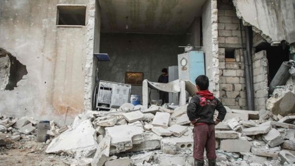 A Syrian boy looks at the fallen wall of a house which was damaged by an airstrike. (AFP Photo)