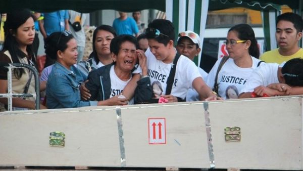 Eva (3rd L), the mother of Filipina worker Joanna Demafelis whose body was found inside a freezer in Kuwait, cries in front of the wooden casket containing her daughter's body shortly after its arrival from Manila at Iloilo International Airport in Iloilo province, central Philippines, on Feb. 17, 2018. (AFP)