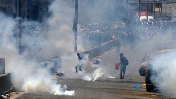 Palestinian men run for cover from tear gas thrown by Israeli forces (AFP/File Photo)