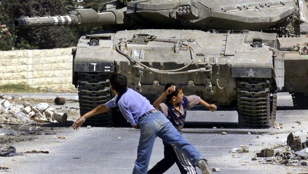 Young Palestinian boys throwing rocks, facing an Israeli tank, (AFP File Photo)