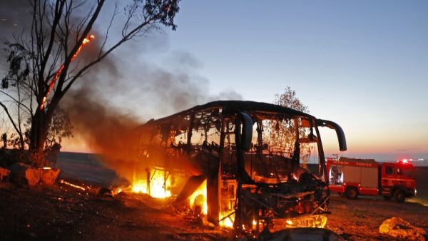 A picture taken on November 12, 2018 shows a bus set ablaze after it was hit by a rocket fired from the Gaza Strip, at the Israel-Gaza border near the kibbutz of Kfar Aza, on November 12, 2018 (AFP)