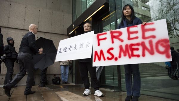Robert Long (L) and Ada Yu hold signs in favor of Huawei Technologies Chief Financial Officer Meng Wanzhou outside her bail hearing at British Columbia Superior Courts following her December 1 arrest in Canada for extradition to the US, in Vancouver, British Columbia on December 11, 2018. 
Jason Redmond / AFP