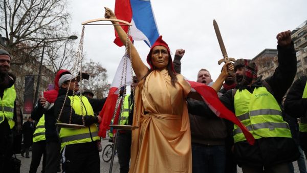 A woman, wearing a Phrygian cap to symbolically represent Justice, and yellow vest protestors 
Zakaria ABDELKAFI / AFP