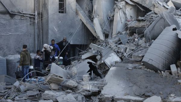 A picture taken on March 26, 2019, shows Palestinians walking amidst next to the rubble of a building in Gaza City, after Israeli air strikes hit dozens of sites across the Strip overnight in response to rocket fire from the Palestinian enclave (AFP)