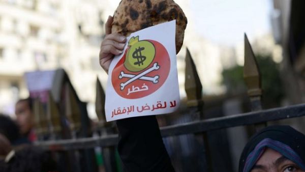 Egyptian protester holds bread along with a flyer in Arabic that reads 'Danger, no to loans that lead to poverty' during a rally in downtown Cairo on April 3, 2013. (AFP/Khaled Desouki)