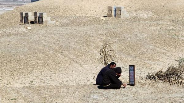 Iraqi men sitting at the grave of their brother, a former policeman who was killed by al-Qaeda sympathizers in 2008 in the Anbar province. (AFP PHOTO/AHMAD AL-RUBAYE)